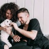 a man and a woman feeding a small dog and smiling